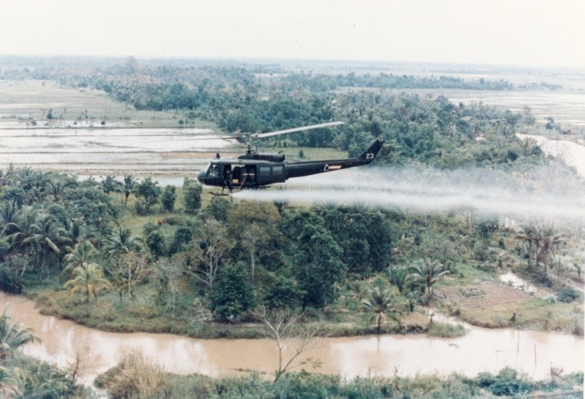 Helicopter Flying Overhead a Forest Misting Agent Orange Below