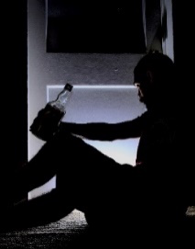 Dark silhouette of an individual with a glass bottle