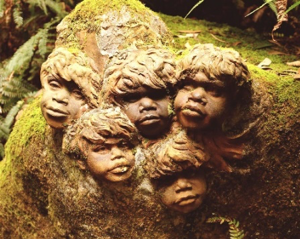 Faces carved into a moss covered rock
