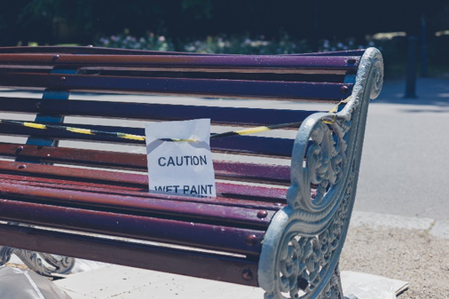 A park bench with a wet paint sign