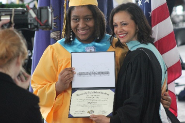 Student and administrator holding diploma and being photographed