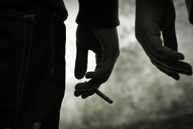 A picture containing hand of one person with cigarette and hand of another person walking side by side