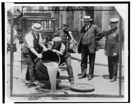 men pouring confiscated liquor down the drain