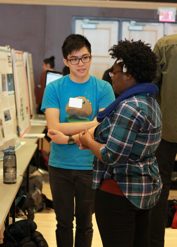 student presenting poster to audience member