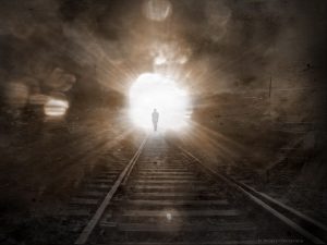 Image of a person walking through a dark tunnel toward the light.