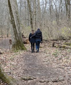 Mother and daughter walking on a hiking trail, one wrapping her arm around the other's waist