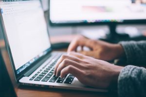 A person is using MacBook Pro and typing words on a word document.