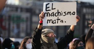 Woman holding a sign reading "el machismo mata," which means machismo kills