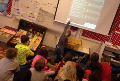 Student using interactive white board in front of her class