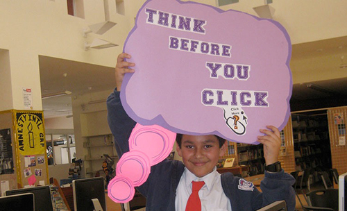 Student holding sign with "Think before you click" slogan