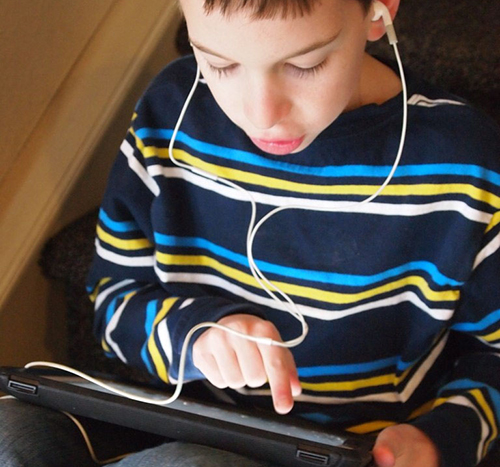 Student using iPad and listening on headphones