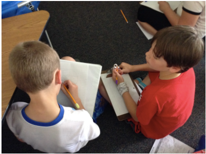 Two students with writing materials and paper involved in a discussion