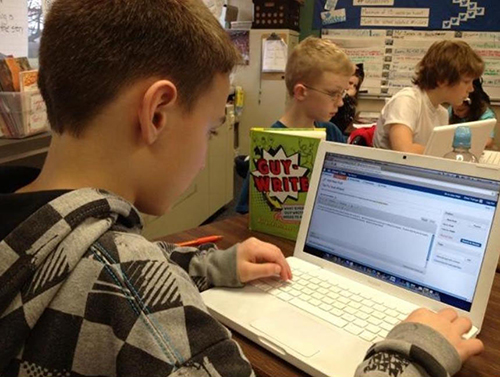 Student writing a blog post on a laptop