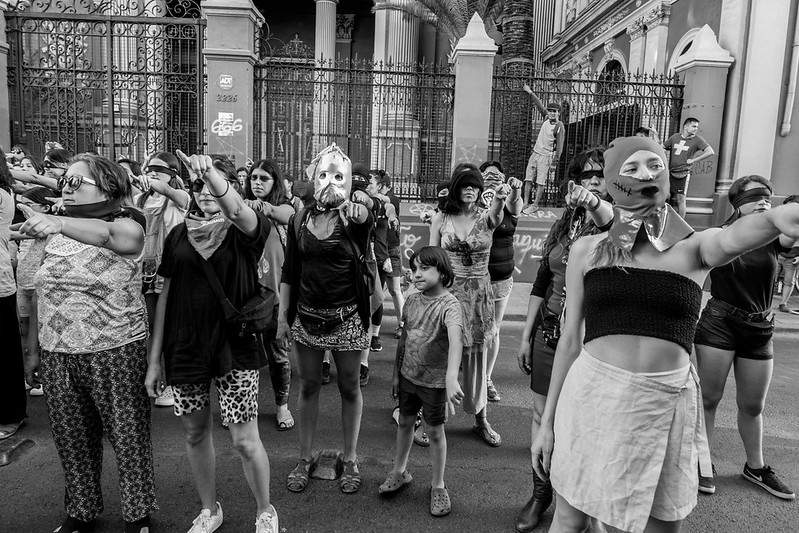 Group of women during a protest. Some are blindfolded or wearing masks.
