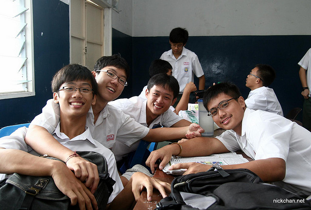 Students leaning in for a group photo in a classroom