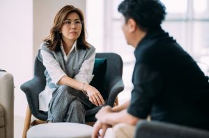 A man and woman talking, seated near a coffee table.