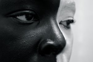 Close-up picture of African American Women with half of face covered in white face paint