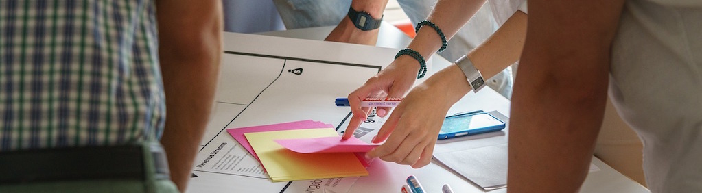 Four people working around a table with notes and markers