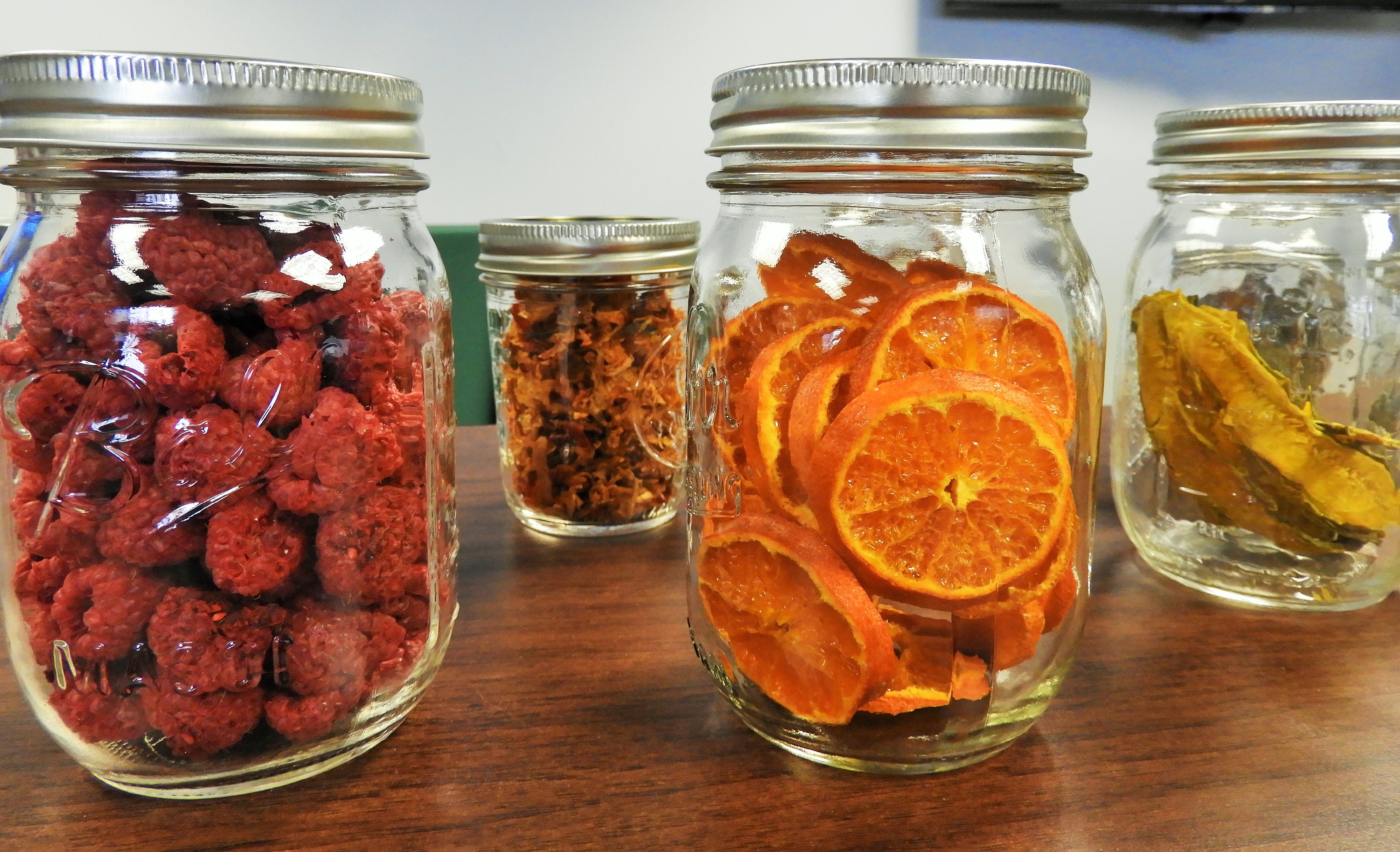 glass mason jars full of dried fruits on a wooden counter